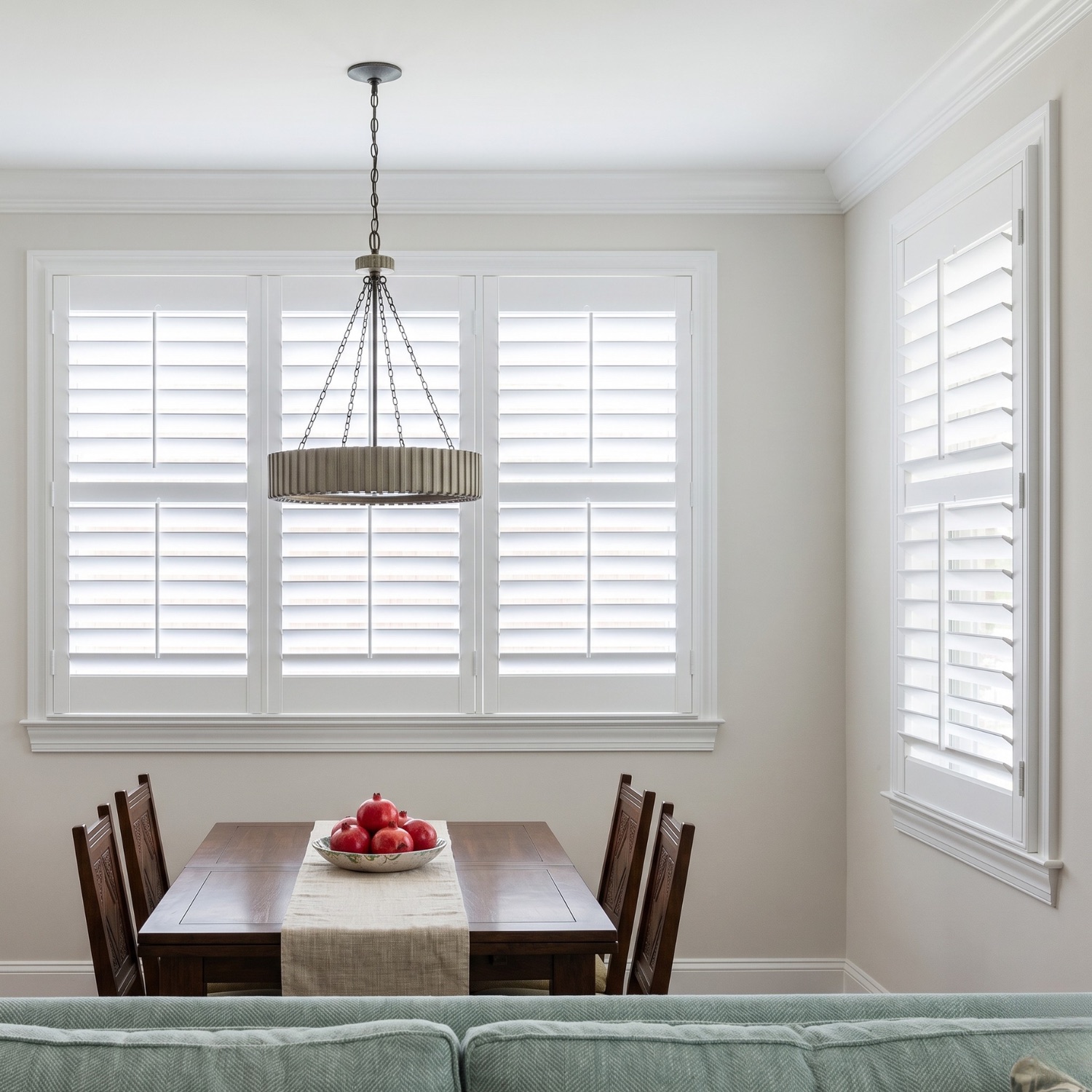 White plantation shutters in a Naples dining room with dark wood table and pendant light