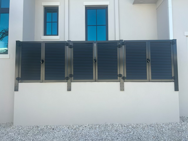 Charcoal louvered gates mounted along a white wall