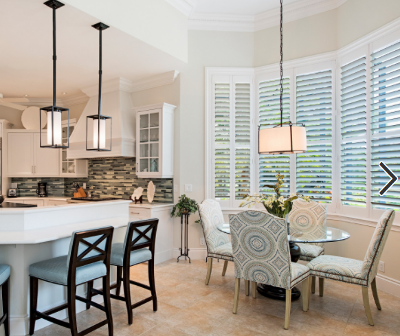 White plantation shutters in a Naples kitchen and dining area with bay window and pendant lighting
