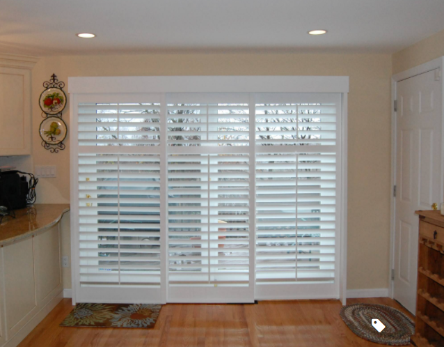 White bypass plantation shutters covering a sliding glass door in a Naples kitchen